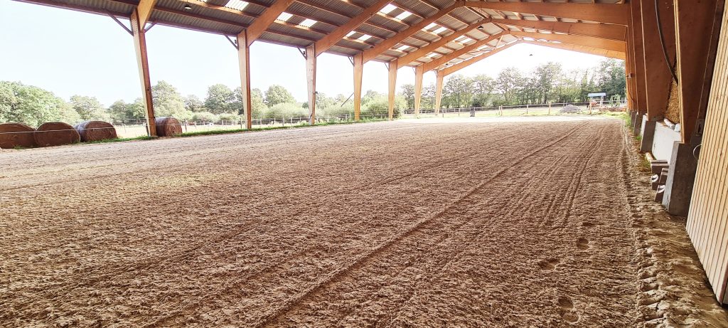 Le manège de l'élevage Keziah avec son ossature bois et son ouverture sur les paddocks avoisinants.